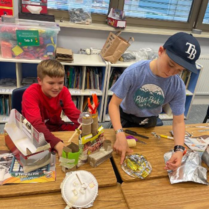 Two elementary students use recyclable materials to create their invention prototypes during Camp Invention