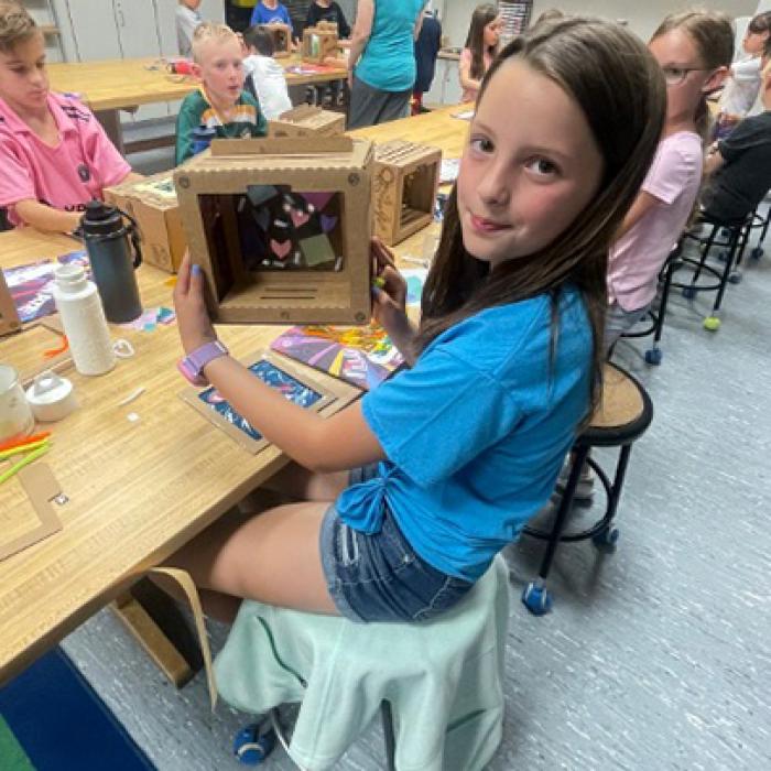 A Camp Invention camper holds up their decorated glow box