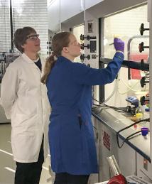 Carolyn Bertozzi in white lab coat instructing a student at Stanford University