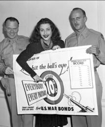 Hedy Lamarr pictured with two soldiers holding War Bonds ad